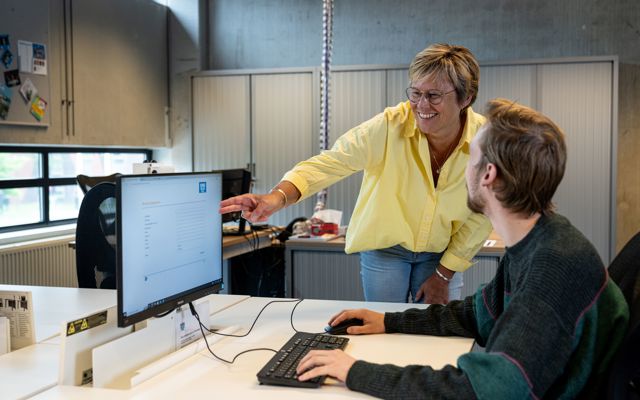 Medewerker Koning Willem 1 College helpt student op computer in klaslokaal