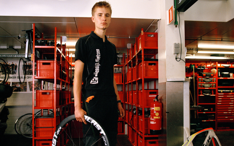 Student fietstechniek met wiel in handen staat in werkplaats