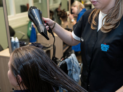 Student kappersopleiding föhnt haren van klant
