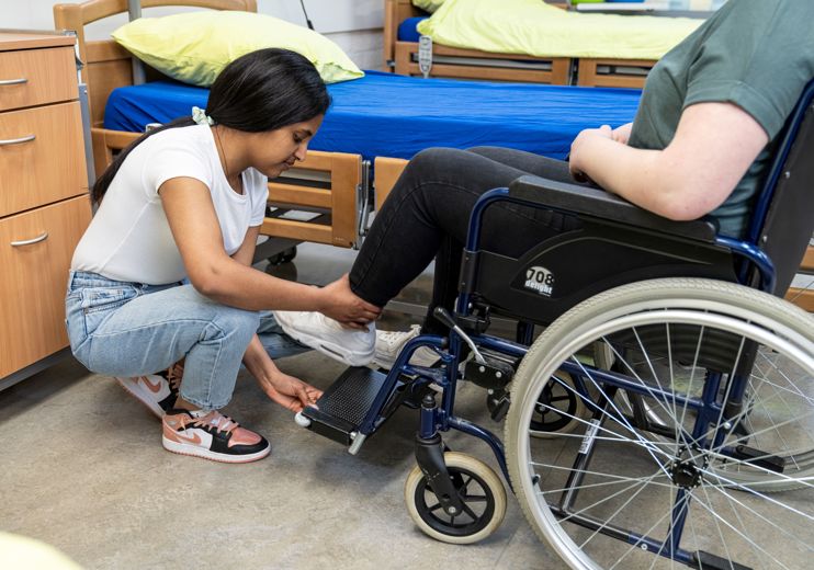 Student helpt cliënt om goed in rolstoel te zitten
