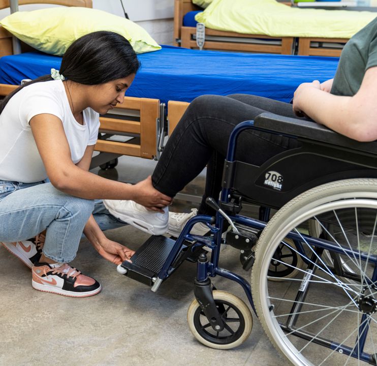 Student helpt cliënt om goed in rolstoel te zitten